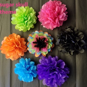 Pu&ograve; includere: Una collezione di fiori di carta velina colorati in tonalit&agrave; di verde, rosa, arancione, blu, viola e nero. I fiori sono disposti su uno sfondo grigio scuro. Il testo "sugar skull theme" &egrave; visibile.