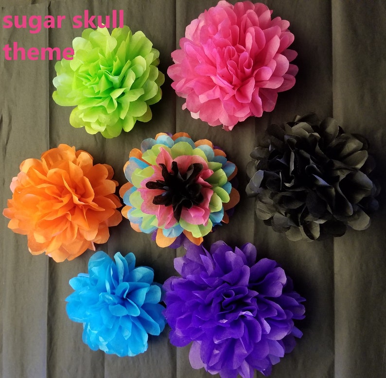 Pu&ograve; includere: Una collezione di fiori di carta velina colorati in tonalit&agrave; di verde, rosa, arancione, blu, viola e nero. I fiori sono disposti su uno sfondo grigio scuro. Il testo "sugar skull theme" &egrave; visibile.