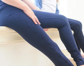 May include: A pair of dark blue leggings with decorative knots along the side seams.
