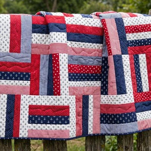 Puede incluir: Una colcha de patchwork con temática náutica compuesta por tiras de tela rectangulares alternas. El diseño incorpora colores rojo, blanco y azul marino con patrones de pequeñas anclas, puntos blancos y finas rayas verticales.
