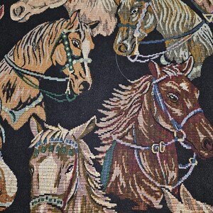 May include: Close-up of a fabric with a repeating pattern of horse heads. The horses are depicted in various shades of brown, tan, and cream, with detailed bridles and manes. The background is black, creating a striking contrast.