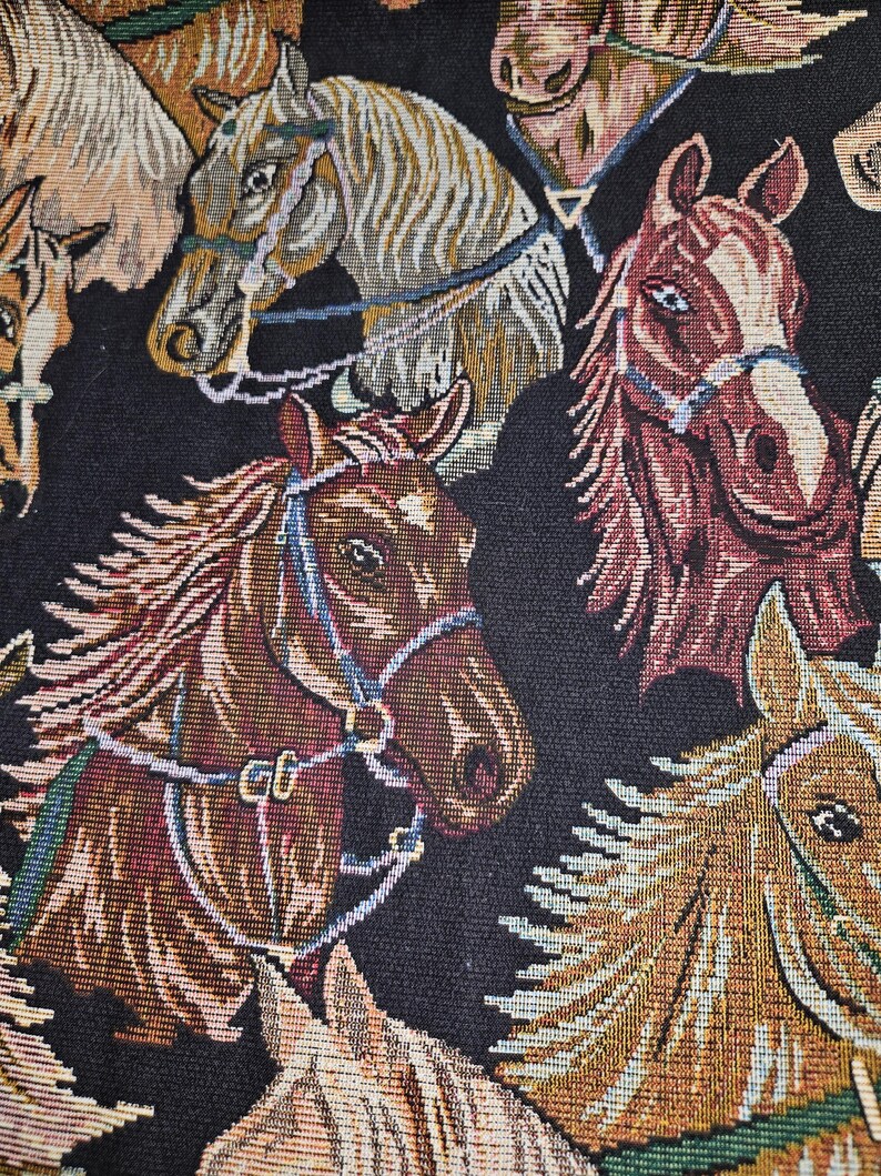 May include: Close-up of a woven fabric featuring multiple horse heads in various shades of brown, tan, and burgundy. The horses are adorned with bridles and harnesses against a black background. The textile has a tapestry-like appearance.