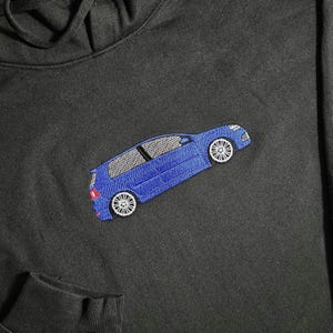 May include: A black hoodie with a blue embroidered car design on the front.