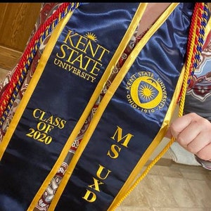May include: A blue graduation sash with gold trim and the text "KENT STATE UNIVERSITY" and "CLASS OF 2020". The sash also has the text "MSUXD" and a gold seal with the text "KENT STATE UNIVERSITY OHIO 1910".