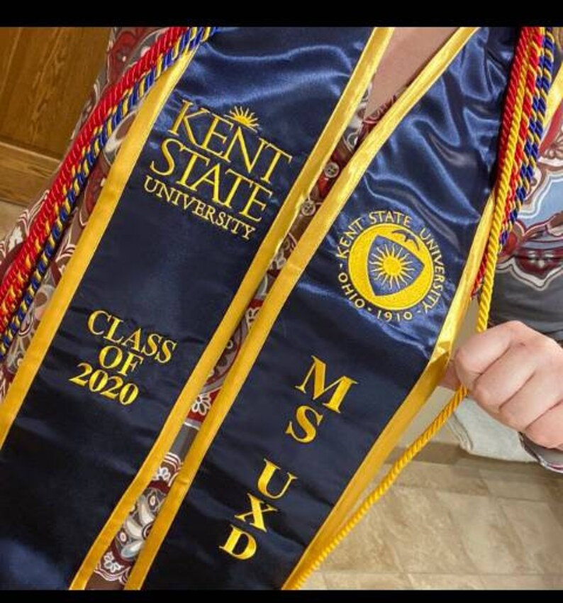 May include: A blue graduation sash with gold trim and the text "KENT STATE UNIVERSITY" and "CLASS OF 2020". The sash also has the text "MSUXD" and a gold seal with the text "KENT STATE UNIVERSITY OHIO 1910".
