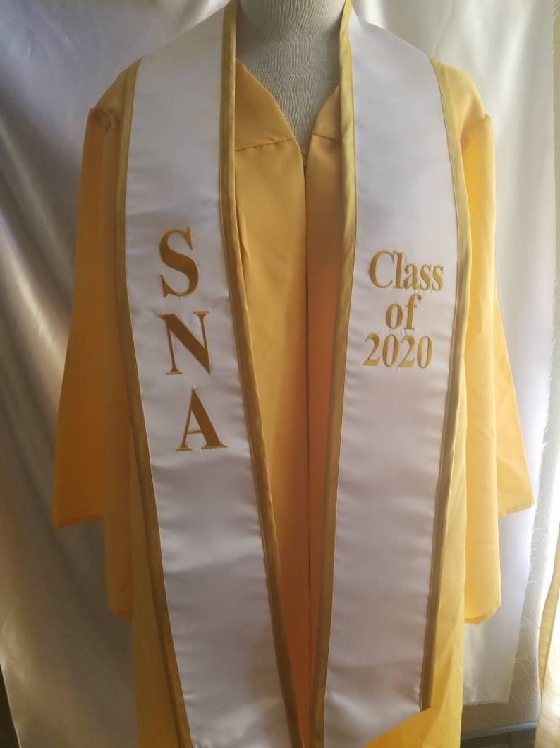 Może przedstawiać: Biała szarfa absolwentka z złotymi lam&oacute;wkami i napisem "SNA" po jednej stronie i "Class of 2020" po drugiej.