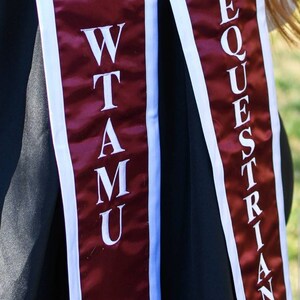 May include: Two maroon graduation sashes with white trim. The sash on the left says "WTAMU" in white letters. The sash on the right says "EQUESTRIAN" in white letters.