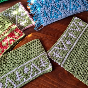 May include: Four crocheted scarves in green, blue, and red with white accents. The scarves have different patterns and textures.