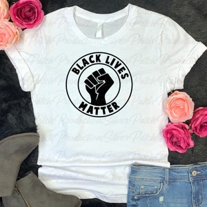 May include: White t-shirt with a black circle graphic that says "Black Lives Matter" with a raised fist in the center.