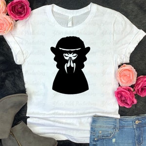 May include: A white t-shirt with a black silhouette of a person with their hands clasped in prayer. The person is wearing a long dress and has a crown on their head.
