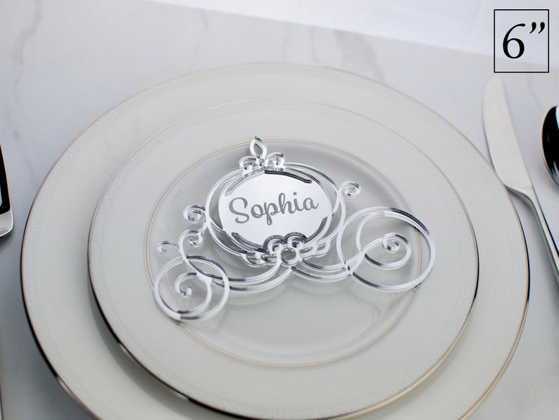 Op de afbeelding: Een zilveren acryl Cinderella-koets plaatskaart met de naam "Sophia" gegraveerd op de voorkant. De koets is 15,24 cm hoog.