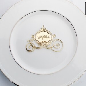 Op de afbeelding: Gouden Assepoester-koets-kaartjeshouder met de naam "Sophia" op een wit bord. De kaartjeshouder heeft een diameter van 10 cm.