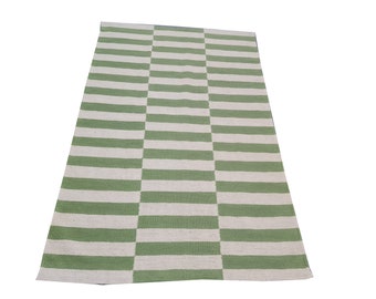 May include: A rectangular rug with a repeating pattern of horizontal stripes in alternating shades of green and off-white. The rug's design is divided into three vertical sections, creating a visually interesting layout. The rug is made of a woven material.
