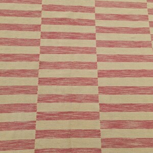 May include: A rectangular rug with a repeating pattern of alternating red and beige horizontal stripes. The stripes are thick and evenly spaced, creating a bold, geometric design. The rug appears to be made of woven fabric.