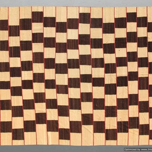May include: A rectangular woven rug with a repeating pattern of alternating dark brown and beige squares. Thin red lines separate the vertical columns of squares. The rug has a simple, geometric design.