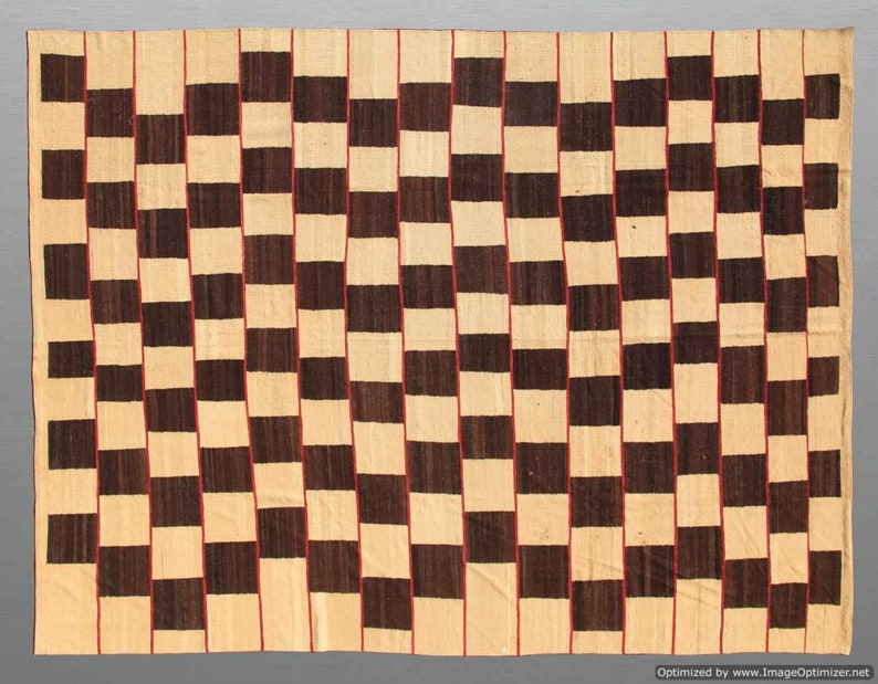 May include: A rectangular woven rug with a repeating pattern of alternating dark brown and beige squares. Thin red lines separate the vertical columns of squares. The rug has a simple, geometric design.