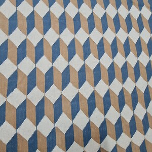 May include: A geometric patterned rug featuring a repeating 3D cube design. The rug's pattern uses white, blue, and tan colors. The rug is made of a woven material and is suitable for home decor.