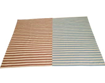 May include: A rectangular rug with a striped pattern. The rug is divided into two sections: one with brown and off-white stripes, and the other with blue and off-white stripes. The stripes run horizontally across the rug.
