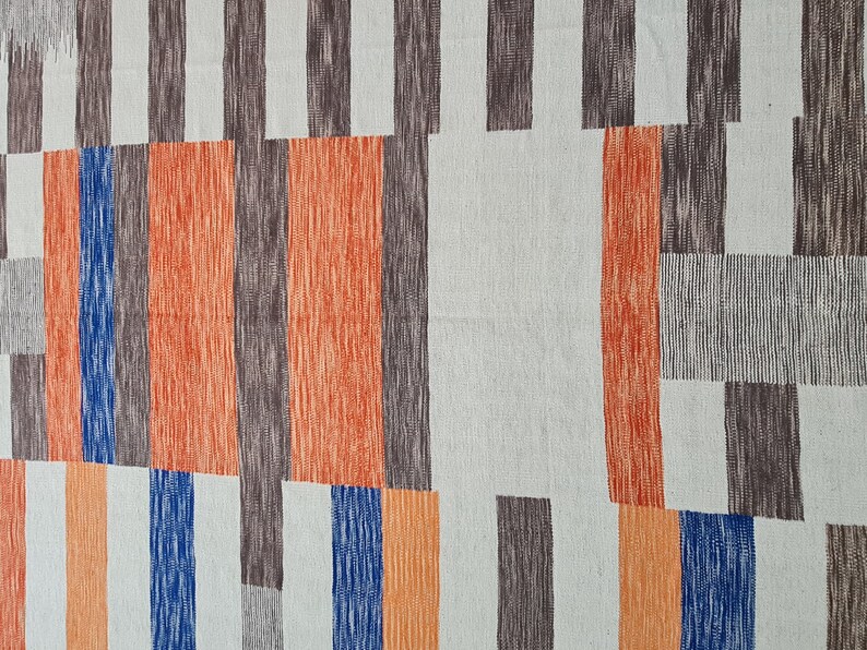 May include: Abstract textile pattern featuring vertical and horizontal rectangular shapes in shades of orange, brown, blue, and gray on a light background. The design has a hand-drawn, textured appearance.