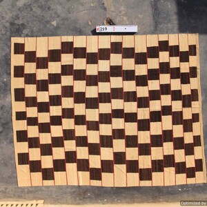 May include: A woven textile with a checkerboard pattern in shades of beige and dark brown. The squares are outlined with thin red lines. The textile is rectangular and appears to be handmade. The tag in the image reads "299".