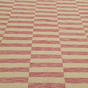 May include: A woven rug with a repeating pattern of alternating red and beige horizontal stripes. The stripes are evenly spaced and create a geometric design. The rug appears to be made of natural fibers.