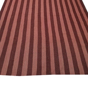 May include: A large, rectangular rug with a striped pattern. The rug features alternating vertical stripes of dark and light reddish-brown colors. The rug is made of a woven material and is displayed on a white background.