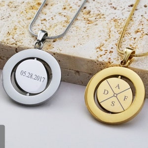May include: Three gold necklaces with round pendants. The pendants have different engravings. One pendant says "I will be always your compass and surround you". Another pendant has the date "05.28.2017" engraved. The third pendant has the letters "D", "A", "F", and "S" engraved.
