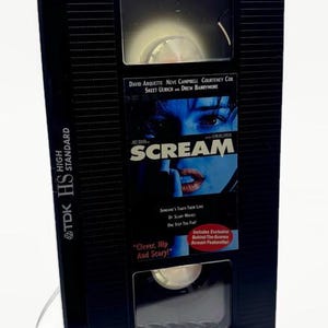 Może przedstawiać: Czarna kaseta VHS do filmu "Krzyk" z tytułem filmu i nazwiskami aktor&oacute;w. Taśma znajduje się w czarnym etui z logo TDK HS High Standard. Widoczny jest r&oacute;wnież tekst "Clever, Hip And Scary!"
