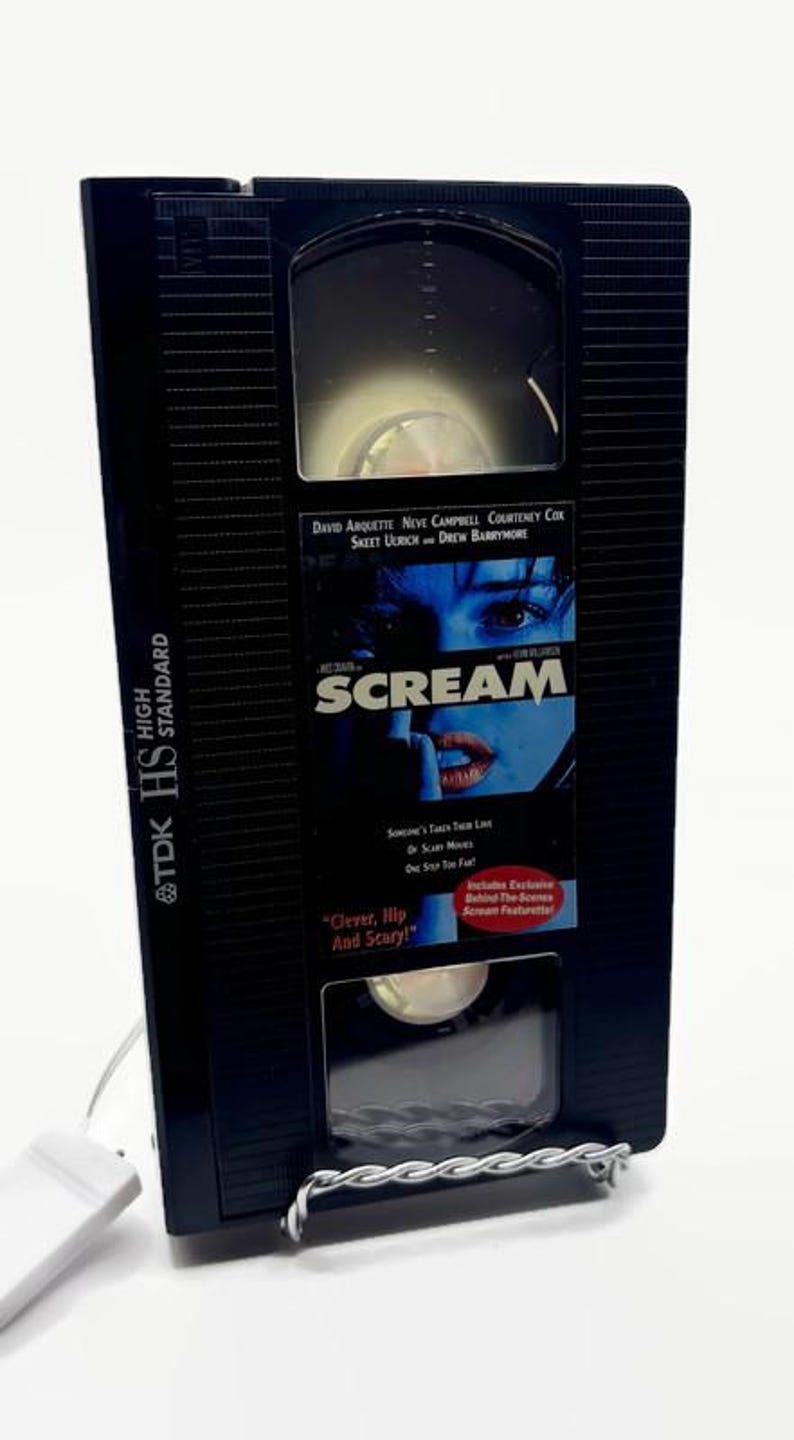 Może przedstawiać: Czarna kaseta VHS do filmu "Krzyk" z tytułem filmu i nazwiskami aktor&oacute;w. Taśma znajduje się w czarnym etui z logo TDK HS High Standard. Widoczny jest r&oacute;wnież tekst "Clever, Hip And Scary!"
