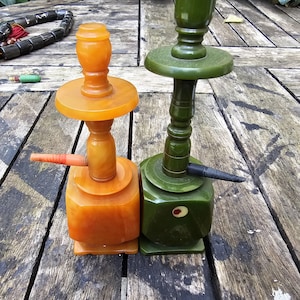Può includere: Due pipe da fumo vintage, una verde e una ambrata, con dettagli decorativi. Le pipe sono realizzate in un materiale liscio e lucido e hanno un design tradizionale.