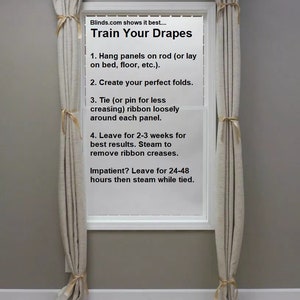 May include: A window with two beige curtains hanging on a black curtain rod. The window has a white frame and a white sill. The window is decorated with a sign that reads "Train Your Drapes" and instructions on how to train drapes.