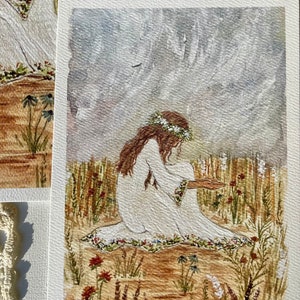 May include: A watercolor painting of a woman in a white dress with a floral crown sitting in a field of wildflowers. The background is a soft, hazy blue.