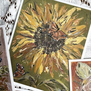 May include: A painting of a sunflower with two butterflies. The sunflower is yellow and brown with a green background. The butterflies are brown and black with white spots.