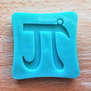 Op de afbeelding: Een turquoise blauwe siliconen mal in de vorm van een vierkant met een pi-symbool erin. De mal heeft een klein gaatje bovenaan om op te hangen.