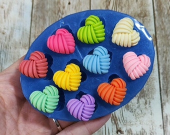 May include: A blue silicone mold with 10 heart-shaped cavities filled with colorful, handmade polymer clay hearts. The hearts are in various shades of pink, red, orange, yellow, green, blue, and purple.