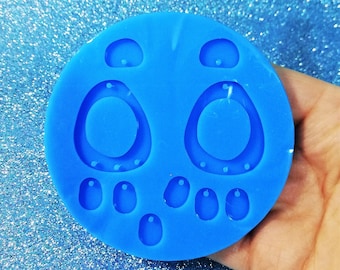 Könnte beinhalten: Blaue Silikonform zum Herstellen von Ohrringen. Die Form hat zwei große ovale Formen mit Löchern für Ohrringstecker und mehrere kleinere ovale Formen zum Herstellen von Ohrringanhängern.