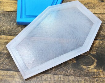 May include: Two silicone moulds for resin casting. One mould is blue and the other is clear. Both moulds are shaped like a coffin.