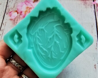 May include: A teal blue silicone mould shaped like a heart with detailed veins. The mould is designed for making resin crafts.