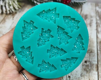 May include: A teal silicone mould with 10 Christmas tree shapes. The mould is designed to create small, detailed Christmas tree decorations.
