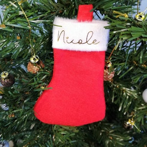 May include: Red Christmas stocking with a white cuff and the name "Nicole" written in gold lettering.