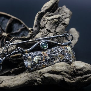 Mixed Metal Organic Necklace with Greenish Blue Sapphire and Topaz, Dark Texture, Statement Edgy Asymmetrical Chain, Silver and Gold Accents. On Dried Cactus Wood with Dried Lemon Behind.
