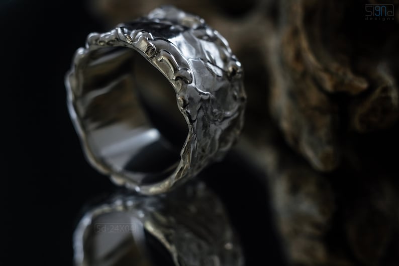 Molten Metal Chunky Ring, Dramatic Jewellery for Men and Women, Unisex Broad Ring with Irregular Edges. On Black Background with Mirror Reflection from Underneath and Dry Cactus Wood Behind.