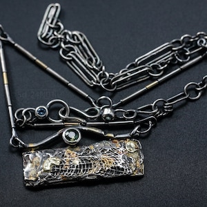 Mixed Metal Organic Necklace with Greenish Blue Sapphire and Topaz, Dark Texture, Statement Edgy Asymmetrical Chain, Silver and Gold Accents. On Black Background.