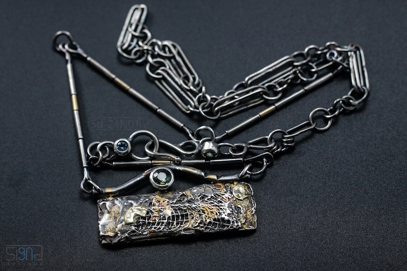 Mixed Metal Organic Necklace with Greenish Blue Sapphire and Topaz, Dark Texture, Statement Edgy Asymmetrical Chain, Silver and Gold Accents. On Black Background.