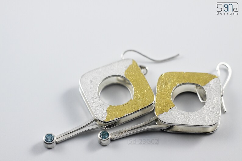 Contemporary dangle earrings with reticulated sterling silver, keum boo 24k gold foil and blue topaz, double-sided jewelry, women wear. On white background.