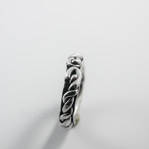 Primitive, raw, organic unisex sterling silver ring with twisted design and patina. On white background. Side view.
