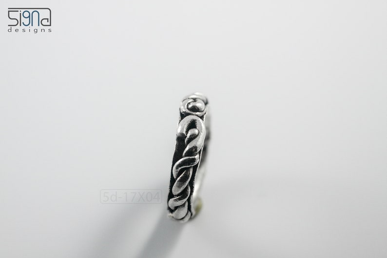 Primitive, raw, organic unisex sterling silver ring with twisted design and patina. On white background. Side view.