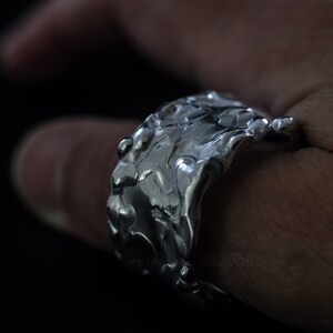 Molten Metal Chunky Ring, Dramatic Jewellery for Men and Women, Unisex Broad Ring with Irregular Edges. On Black Background, on Thumb.