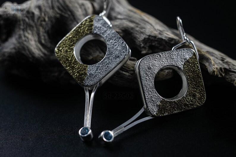Contemporary dangle earrings with reticulated sterling silver, keum boo 24k gold foil and blue topaz, double-sided. On Dry Cactus Wood.