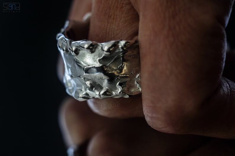 Molten Metal Chunky Ring, Dramatic Jewellery for Men and Women, Unisex Broad Ring with Irregular Edges. On Black Background with Mirror Reflection from Underneath. On Finger.